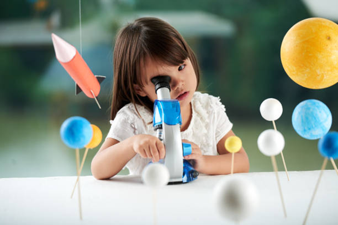 Ni&ntilde;a mira por un microscopio