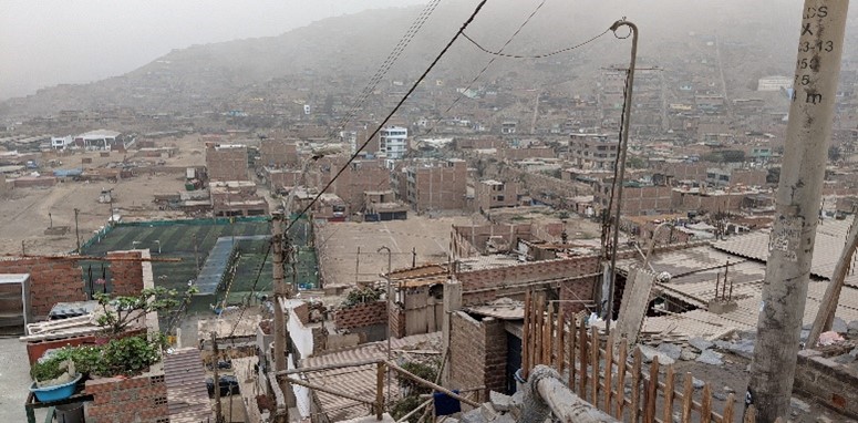 A la derecha Lurigancho-Chosica visto desde lo alto del cerro. Se aprecia el "urbanismo de aluvión". También la cancha deportiva construida por Cesal